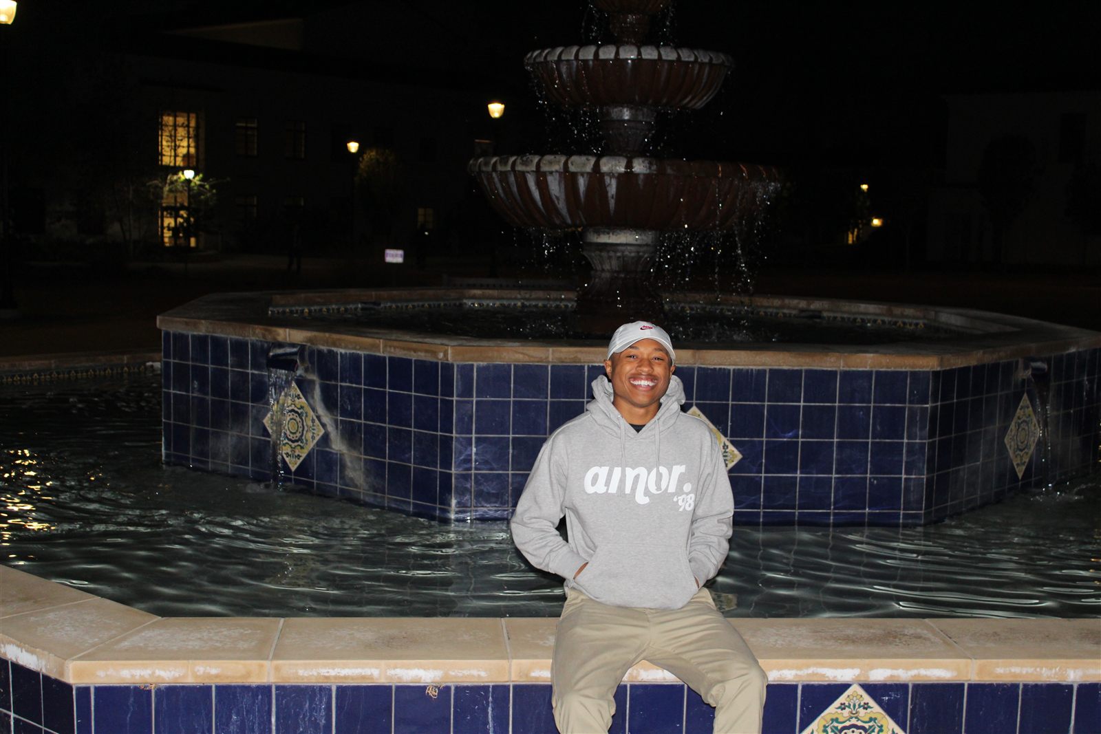 Elijah on campus at night in an amor '98 hoodie