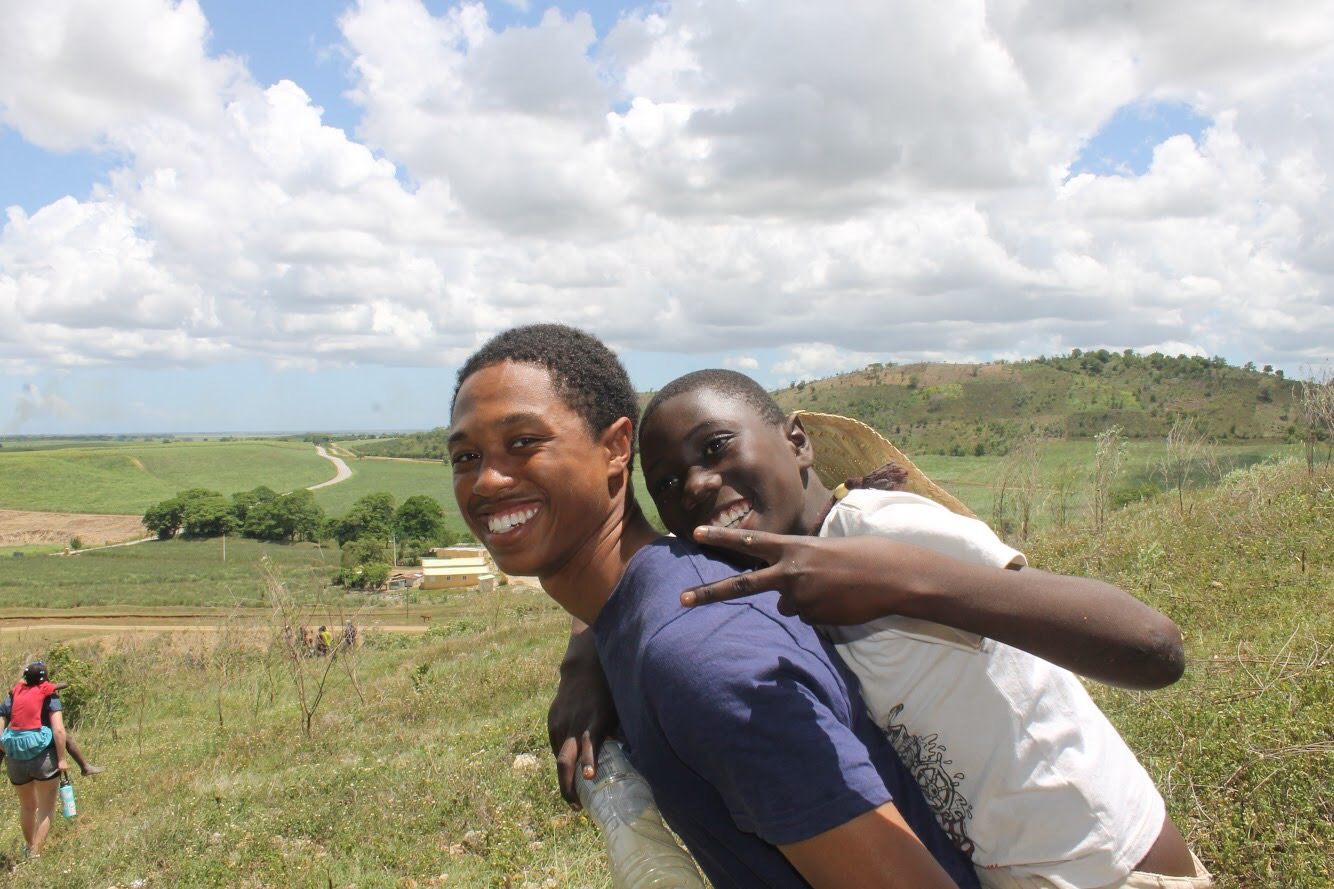 Elijah with a child on his back in the Dominican Republic